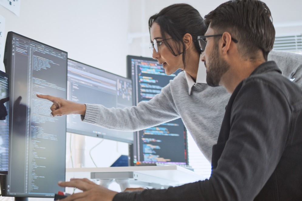 Man and woman looking at screen with code